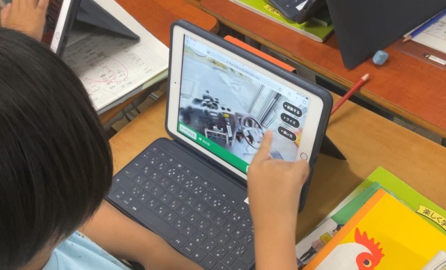 児童がタブレットで消防車の運転席を見る様子